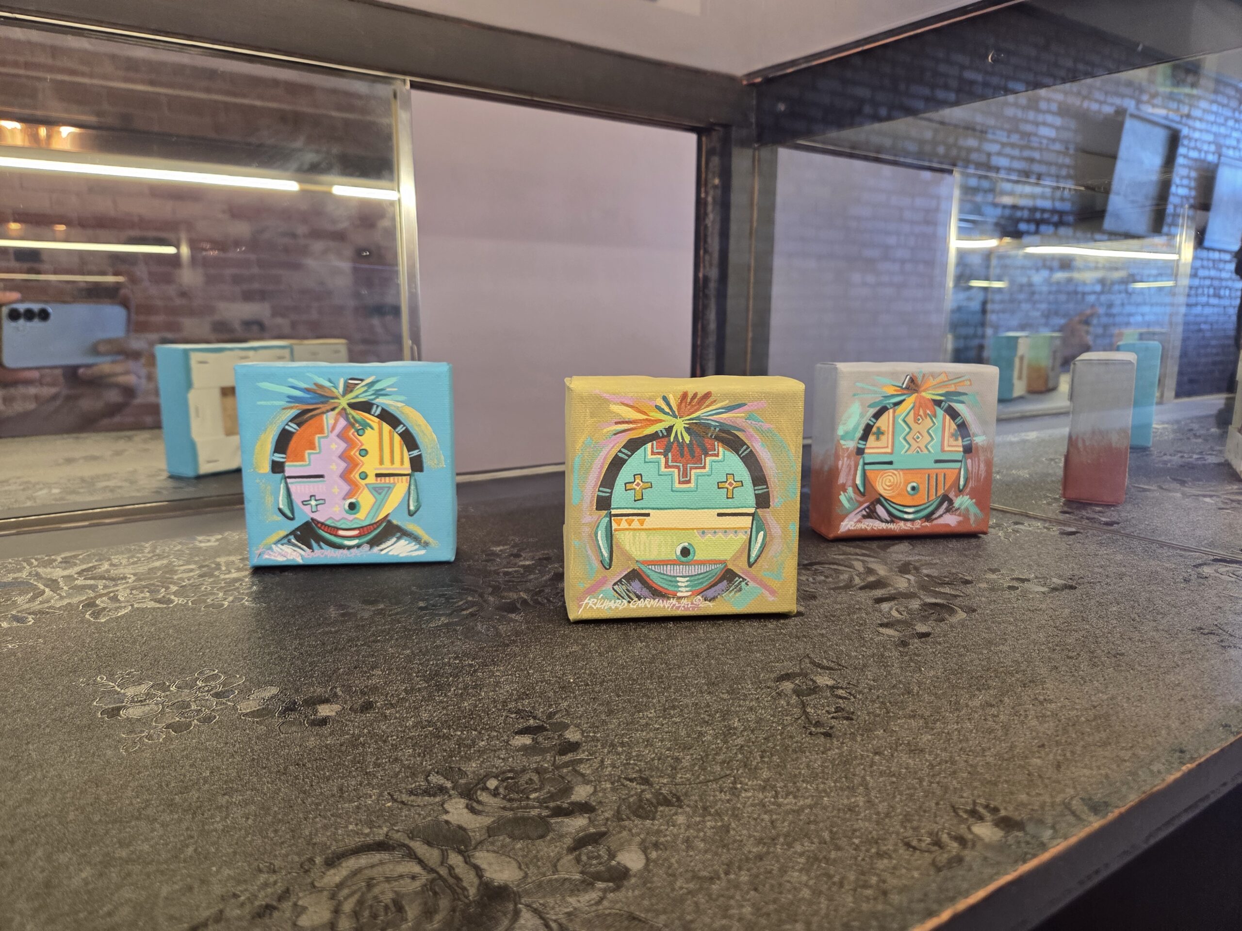 Three small framed colorful pieces resting on a ledge