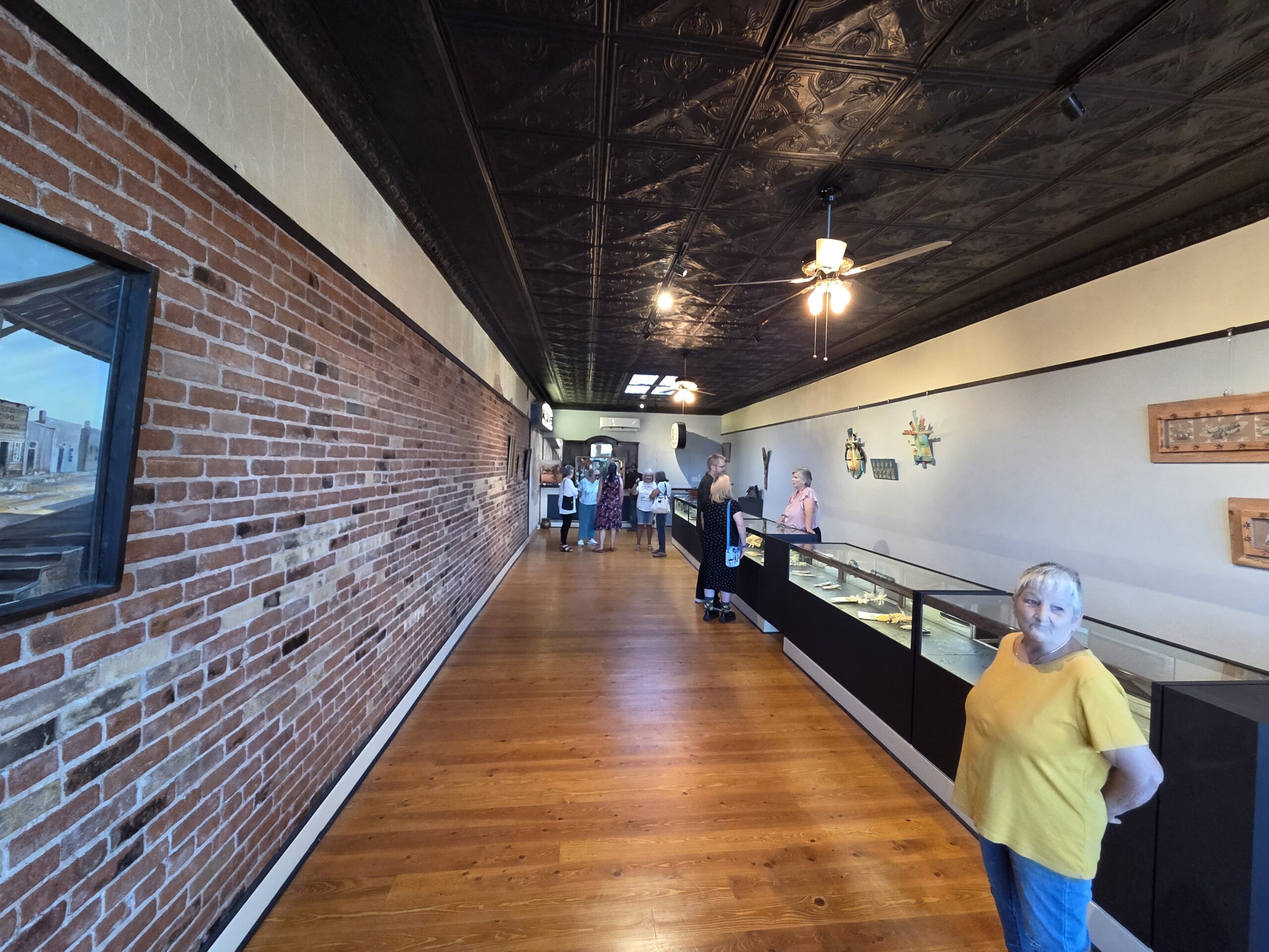 The single open gallery room of The Gandy Dancer Gallery, brick walls and wood floors hung with local art