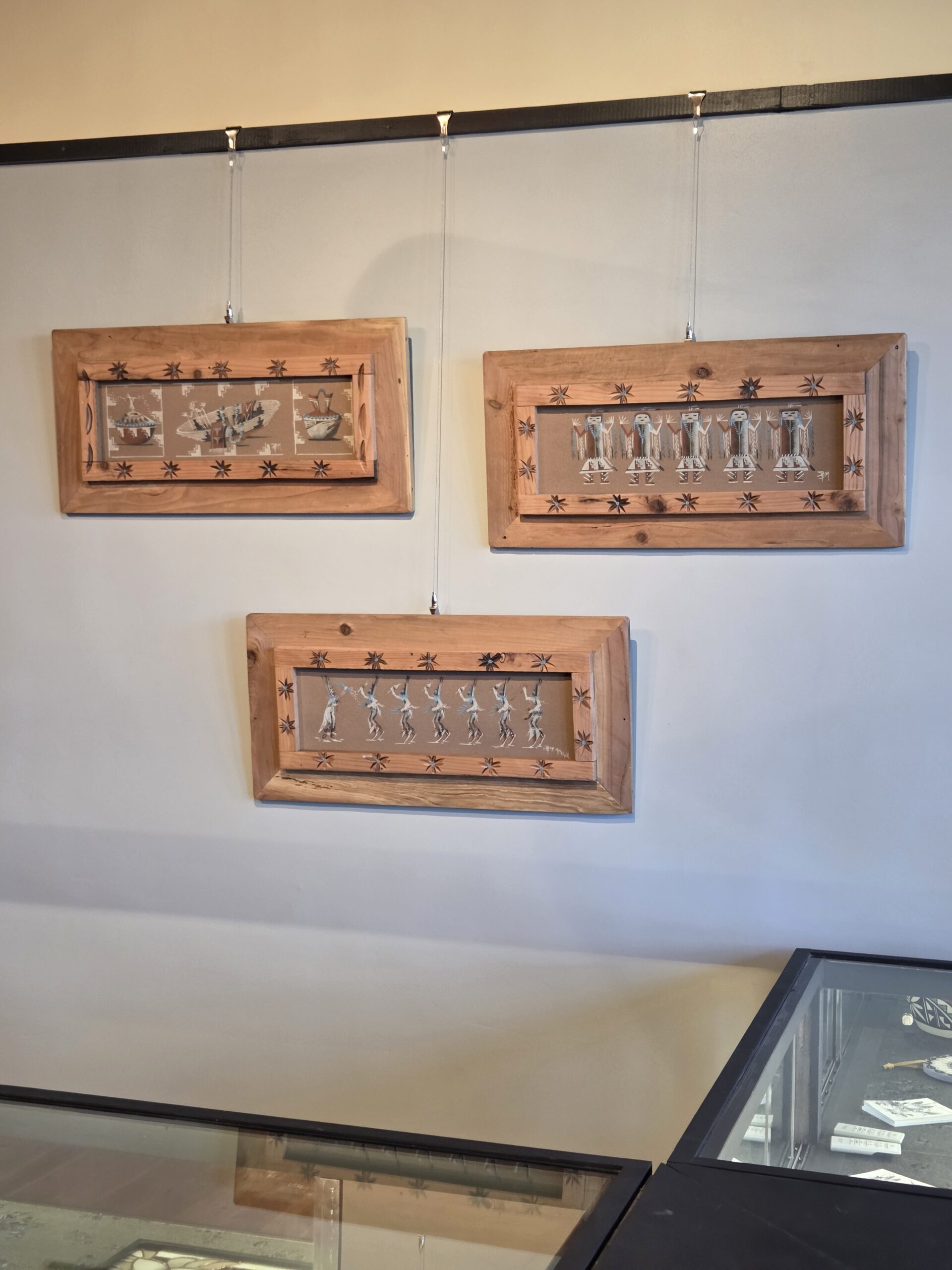 Framed works hung above a display case